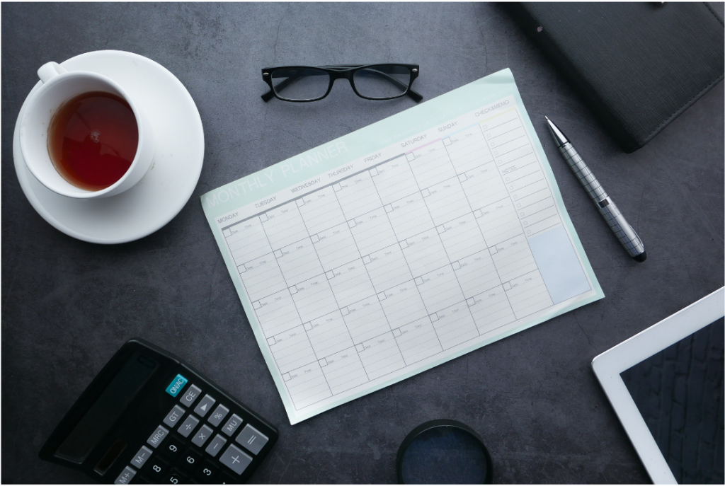 Bureau avec un calendrier, tasse de café, lunettes, calculatrice