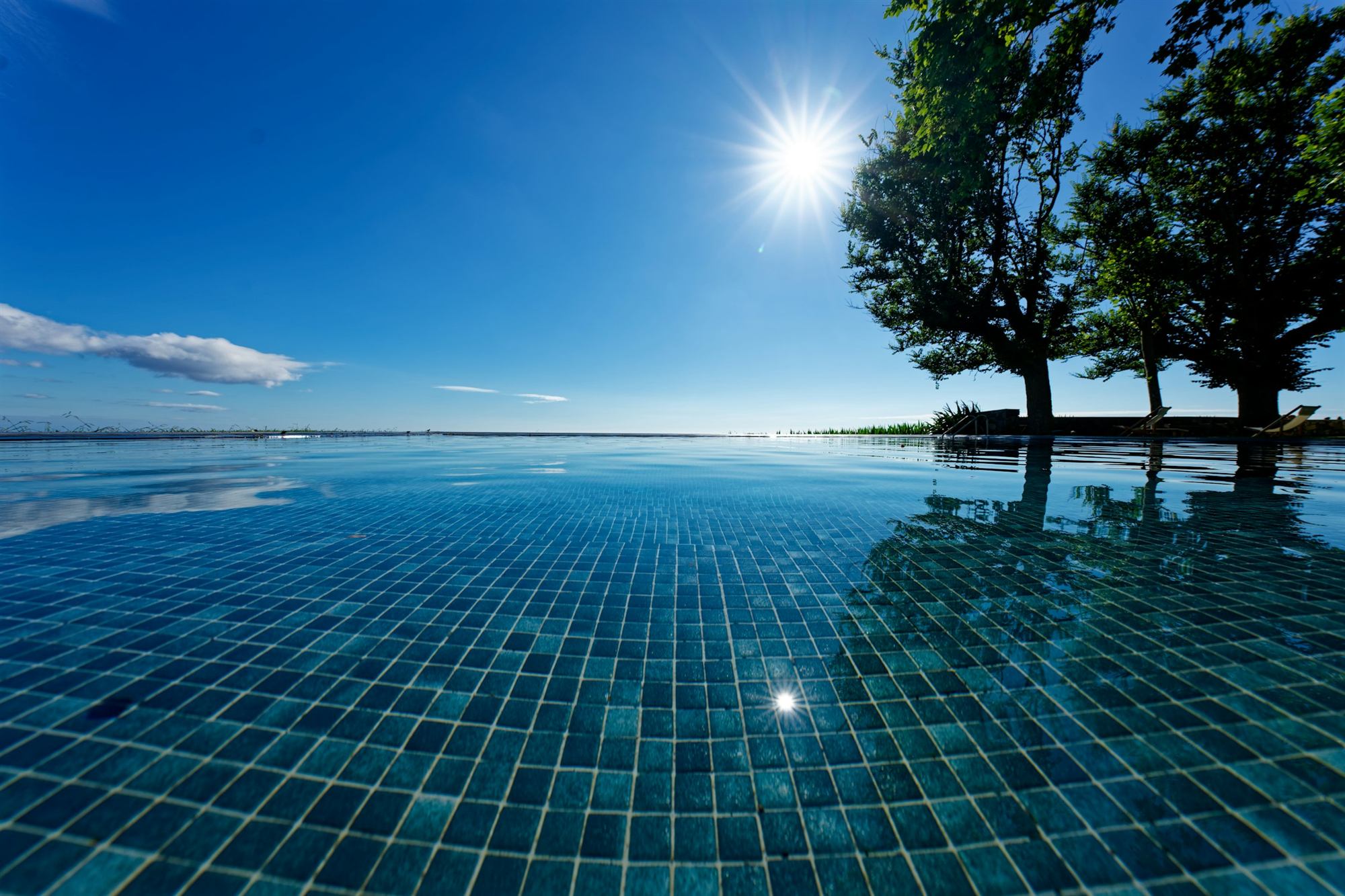 Piscine à débordement en plein soleil, face à l’horizon